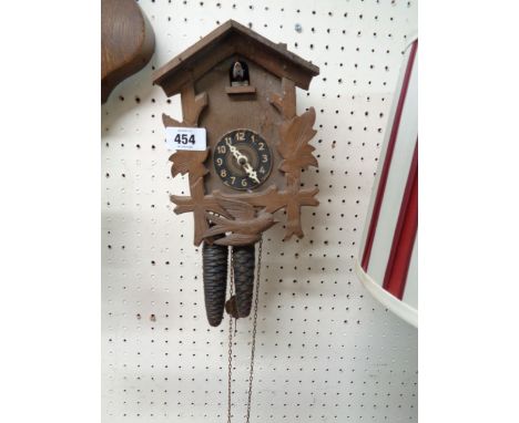 A vintage tourist ware stained wood cuckoo wall clock with twin metal acorn pattern weight driven movement