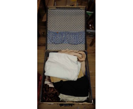 A vintage suitcase with travel stickers containing a quantity of various fabric including velvet, cotton, etc.