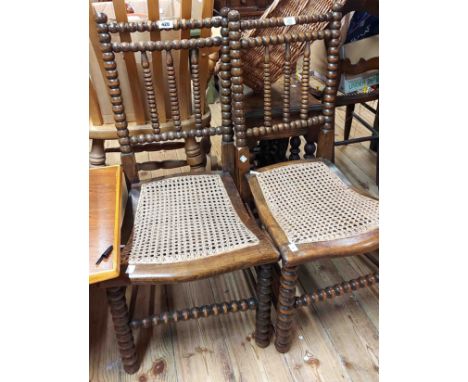 A pair of old stained beech framed bobbin turned standard chairs with rattan seat panels