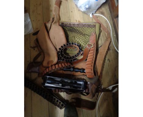 A box containing a quantity of shooting equipment including ammunition belts, canvas gun cases, shooting bag, scopes, etc.