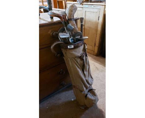 A old canvas and leather golf bag containing a quantity of vintage clubs, fencing foil, etc.