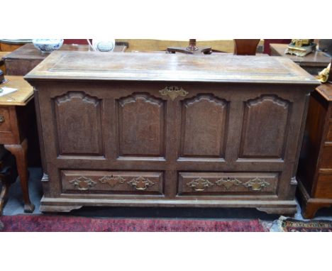 A George III oak mule chest, the hinged top enclosing a deep well with fitted drawers to one end over a four panel front and 