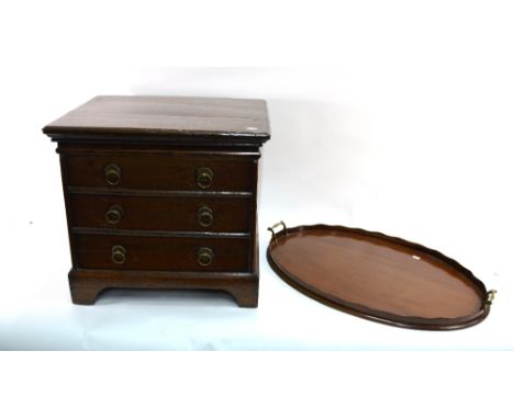 An early 19th century oak cellarette, hinged lid with divided interior, three dummy drawers with brass handles raised on brac
