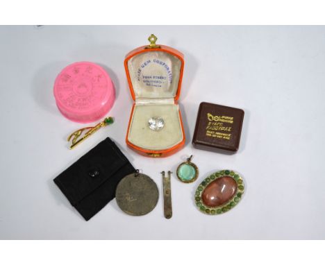 A collection of various items including jade tie clip, an oval brooch set with pink and green stones, white stone in fitted b