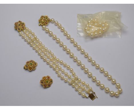 A suite comprising a single row uniform cultured pearl necklace on yellow metal stylised flower snap set with rubies and sapp
