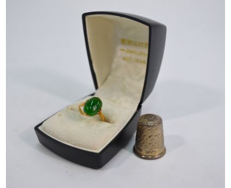 An oval green jade single stone ring, yellow metal claw setting stamped 18ct to/w a Charles Horner silver thimble, Chester (2