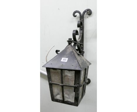 A wall hanging metal electric lantern with large ornate metal bracket 