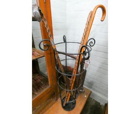 A metal stick stand, three walking stick and a rustic magazine rack 