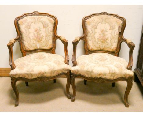 A pair of French walnut framed armchairs on cabriole legs upholstered in cream and floral tapestry 