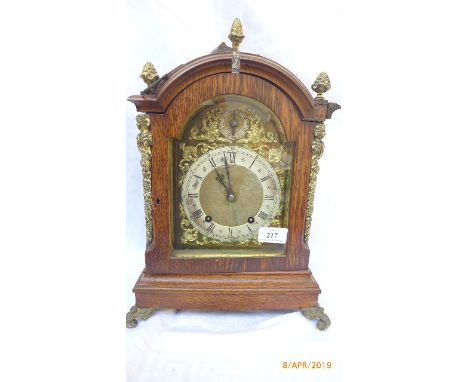 Decorative oak hooded cased German mantel clock with gilded and steel dial with roman numerals, pineapple head decoration on 