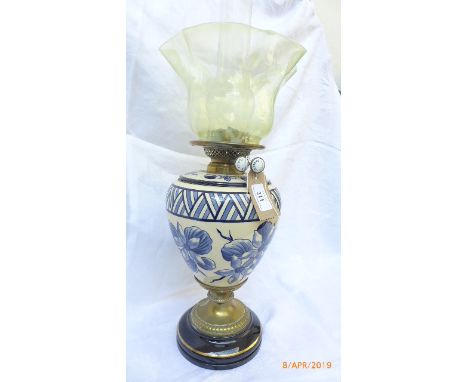 Early 20th century oil lamp on brass and circular ebonised plinth, the central bowl in blue and white floral design and green