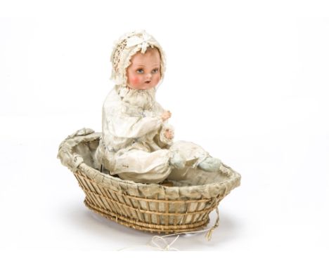 An unusual pull-along baby in cot automaton 1930s, The composition headed baby seated in a basket, cream clothes and basket l
