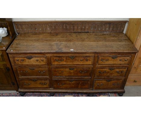 A 17th century and later oak dresser base, the nine crossbanded drawers with brass swan neck handles raised on turned feet a/