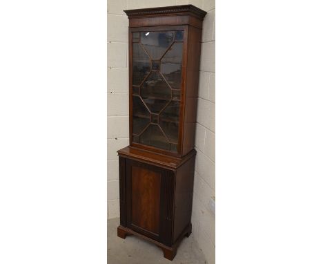 An Edwardian mahogany bookcase cabinet with astragal glazed door enclosing three shelves over a fluted panelled door, raised 