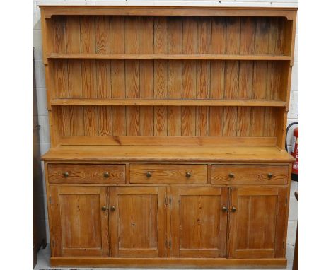 A large stained pine dresser, the plate rack with two open shelves on a base with three drawers over panelled cupboard doors,