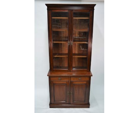 An Edwardian walnut chiffonier bookcase, with pair of glazed door enclosing adjustable shelves over two short drawers to a pa