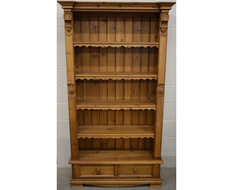 A Continental carved pine open bookcase with four shelves over two drawers raised on bracket feet, 200 cm high x 110 cm wide 