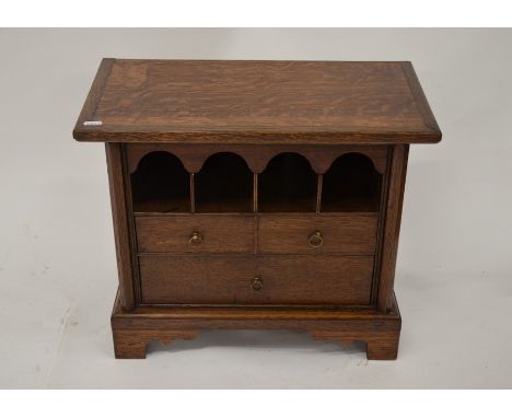 A small table top oak cabinet with four arched pigeon holes above two short drawers over one long drawer, brass ring pulls, 3