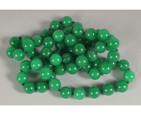 A STRING OF GREEN JADE BEADS. 28" long