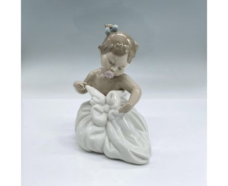 Glazed porcelain figure of a baby girl with a pink pacifier in her mouth wrapped up in a white blanket. Nao backstamp. Dimens