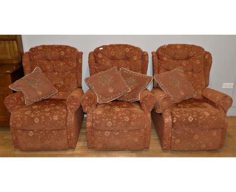 Three matching manual recliner armchairs, upholstered in a pale burgundy floral fabric. W69cm, H103cm, (3) 