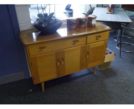 An Ercol light elm small sideboard, with one long and one short drawer above a pair of cupboard doors beside a single door, o