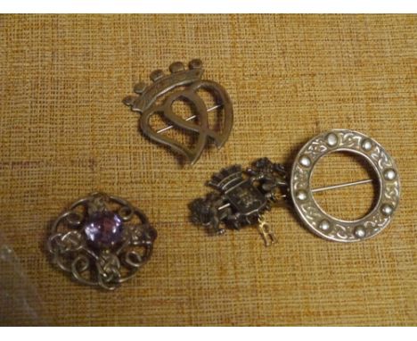 A group of silver brooches comprising: a luckenbooth brooch; a Celtic brooch of kilt pin type; a Celtic brooch set with an am