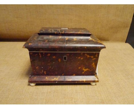 A Regency tortoiseshell tea caddy, the pagoda cover opening to reveal twin lidded compartments, raised on ivory ball feet. 13