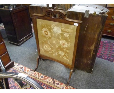 An Edwardian mahogany framed firescreen, with scroll and fret carved crest, raised on hipped downswept legs, and enclosing a 