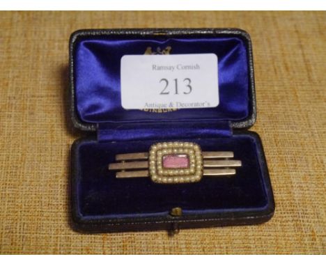 An Edwardian pink engine-turned enamel and seed pearl brooch, the oval enamel panel within twin bands of pears, on a triple b