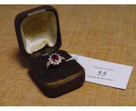 A ruby and diamond cluster ring, the oval-cut ruby within a band of brilliant cut diamonds on diamond-set shoulders and a 9ct