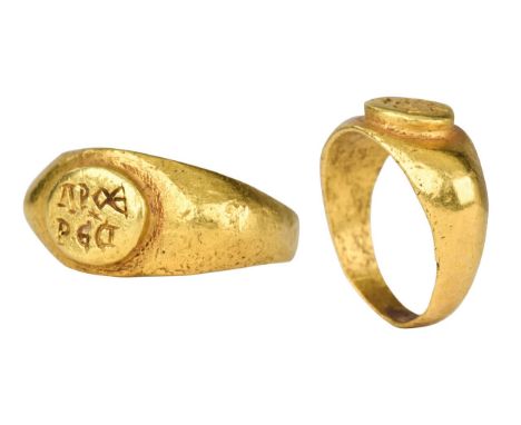 Ca. 200 ADA gold finger ring of a round hoop widening to the faceted shoulder bearing a raised oval bezel engraved with an in