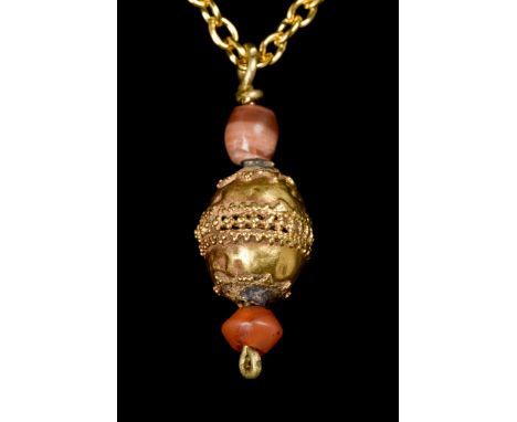 Ca. 400-300 BCA gold pendant in the form of a globe with centre panel band of decoration, inbetween two carnelian beads. The 