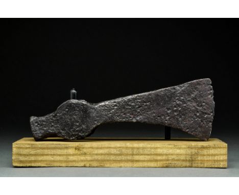 Ca. 900-1000 ADA forged-iron axe head of a hefty form with a perforated socketing shaft, a dense neck, and a vertically orien
