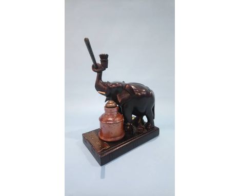 An inkstand in the form of an ebonised elephant standing on a book, with stoneware inkwell