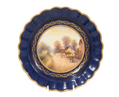 A Royal Worcester blue ground plate, painted by Rushton with a village scene, gilt patterned borders, fluted edge, inscribed 