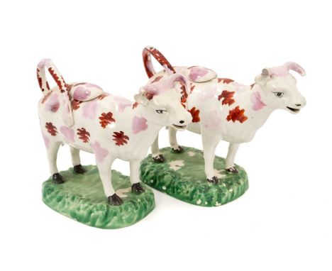 A pair of early 19th century Swansea lustre cow creamers, painted with splashes of red and pink, on naturalistic green-painte