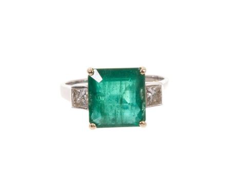 Emerald and diamond three-stone ring with a rectangular step cut emerald estimated to weigh approximately 4.77 carats, flanke