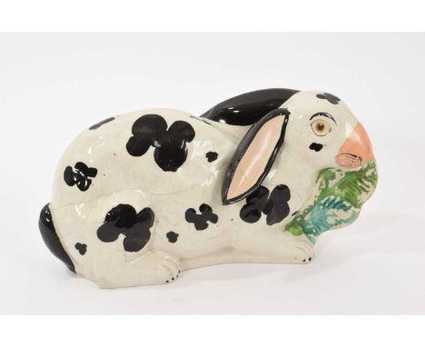 A rare Staffordshire pottery model of a rabbit, circa 1850, painted in black and white and shown nibbling on leaves, 24cm wid