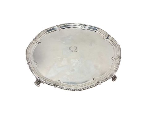 Early 20th century silver salver of shaped circular form with engraved armorial crest and gadrooned border on four classical 