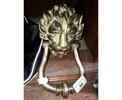 A brass door knocker in the shape of a lions head 