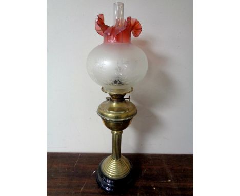 A brass oil lamp with two tone etched glass shade 