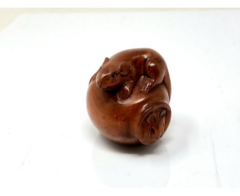 A carved Chinese hardwood netsuke - Rat climbing on a pot 