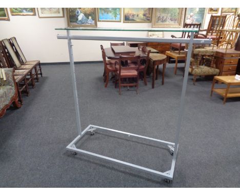 A metal adjustable shop clothes rail with glass shelf 