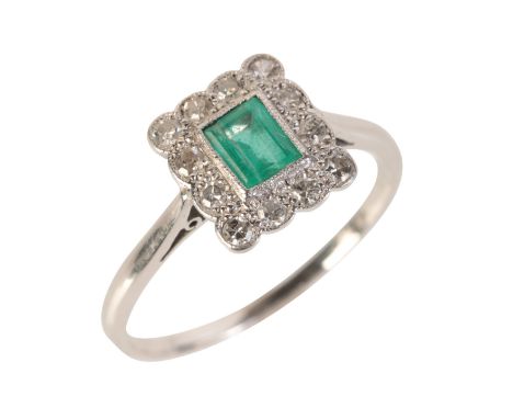 AN EMERALD AND DIAMOND CLUSTER RINGin 18ct white gold, set with a step cut emerald of c.0.38 carats, held in a milgrained rub