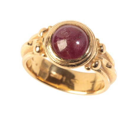 MASSIMO MARIA MELIS: A ROMAN REVIVAL RUBY RINGin 20ct gold, set with a ruby cabochon held in a bezel setting to stylised shou