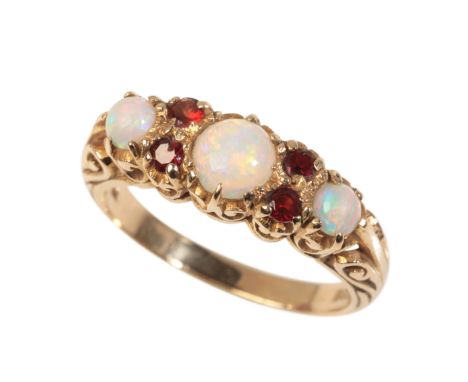 A VINTAGE OPAL AND GARNET RINGin 9ct gold, set with three graduated round opals, alternating with pairs of round cut garnets 