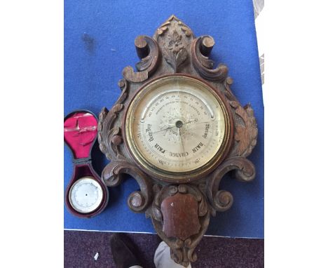 A carved oak barometer by Elliott Brothers, of cartouche form decorated with floral motifs, with a 19th century compass, in l
