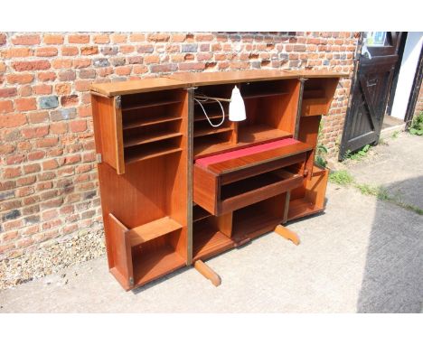 A 1960s teak home office cabinet with fitted interior, pull-out writing surface, adjustable lamp, shelves and drawer, 33" wid