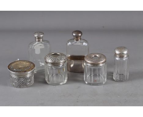 A silver topped hip flask with fitted silver cup, two silver topped hair tidy jars and three other silver topped jars 